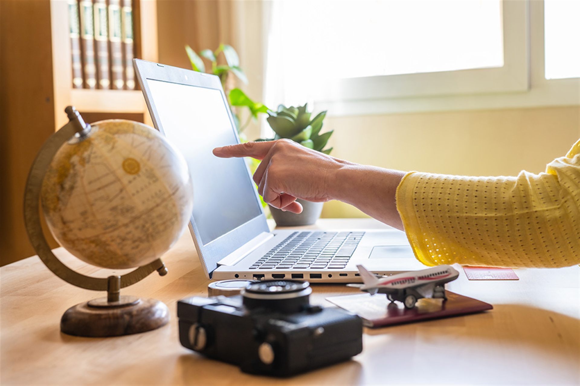 Travel planning — laptop, globe, and camera on a desk